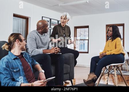 Eh bien toujours la valeur de son expertise et des paroles de sagesse. un groupe d'hommes d'affaires ayant une réunion et discutant des idées dans leur bureau au travail. Banque D'Images