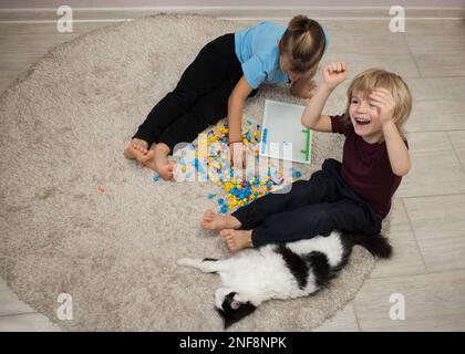 2 garçons d'âge préscolaire pieds nus jouent ensemble avec une mosaïque multicolore, assis sur un tapis . Jeux éducatifs, activités quotidiennes intéressantes pour les enfants. dôme Banque D'Images