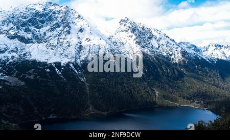 Czarny Staw Pod Rysamy ou lac Black Pond près de la cabane de montagne Morskie Oko Snowy dans les montagnes polonaises de Tatry, vue sur les drones, Zakopane, Pologne. Vue aérienne prise de magnifiques collines verdoyantes et montagnes dans des nuages sombres et reflet sur le lac Morskie Oko. Destination touristique de voyage Banque D'Images