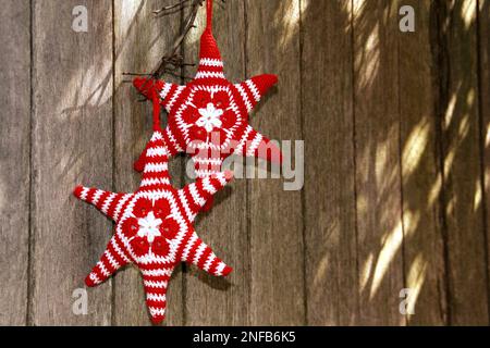 étoiles en crochet blanc et rouge faites à la main suspendues à l'extérieur sur une clôture en bois Banque D'Images