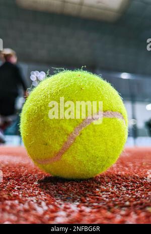 Photo détaillée d'un paddle ball sur le sol du court de paddle-tennis intérieur et d'amis à trois joueurs en arrière-plan du court Banque D'Images