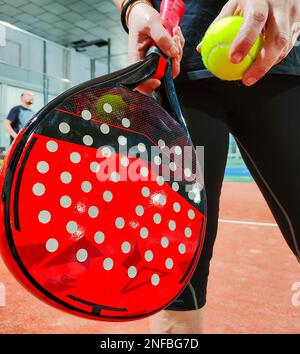 Femme se préparant à lancer une balle verte avec sa raquette de paddle-tennis dans un court intérieur Banque D'Images