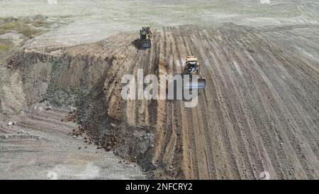 Les bulldozers poussent le sol sur un immense site minier. Banque D'Images