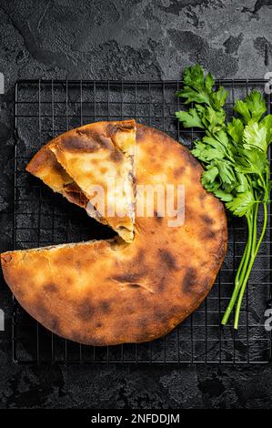 Tarte d'ossète cuite avec de la viande de boeuf et des herbes. Arrière-plan noir. Vue de dessus. Banque D'Images