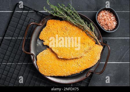 Weiner Schnitzel allemand, cru et fait maison. Arrière-plan noir. Vue de dessus. Banque D'Images