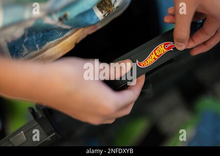 Ternopil, Ukraine - février, 2023: Garçon colle un sticker Hot Wheels. Banque D'Images