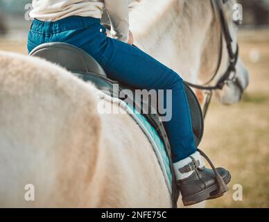 .Sports, équitation et chaussures de fille à cheval dans la campagne pour le passe-temps, l'équitation et l'apprentissage. Cowgirl, été et pâturage avec jockey enfant et animal de compagnie sur Banque D'Images