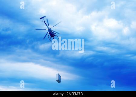 Vue de dessous de l'hélicoptère avec chargement volant dans le ciel spectaculaire. Banque D'Images