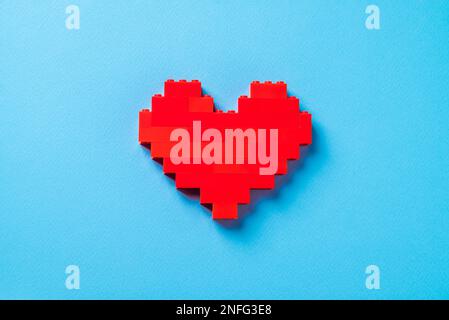 Coeur rouge en briques de plastique sur fond bleu Banque D'Images
