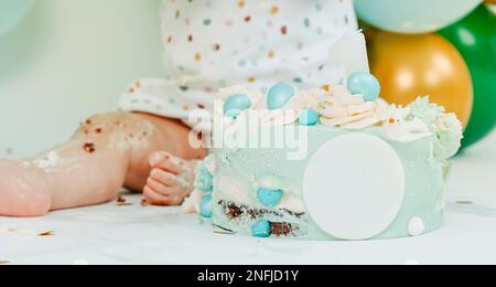 gros plan d'un joli gâteau bleu et d'un bébé lors d'une fête de gâteau de smash pour leur premier anniversaire, et quelques ballons de différentes couleurs en arrière-plan Banque D'Images