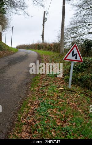 Route dans la campagne et un signe de plusieurs tours. Panneau d'avertissement pour le chemin d'enroulement. Banque D'Images