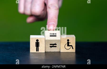 Symbole de l'égalité des droits des personnes handicapées. La main tourne le cube en bois et change le signe inégal en signe égal. Banque D'Images