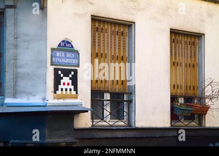 Vue sur la rue du coin de la rue des Vinaigriers avec Une mosaïque de mosaïques d'envahisseurs d'espace, Graffiti et Une fenêtre à volets, Paris France Banque D'Images