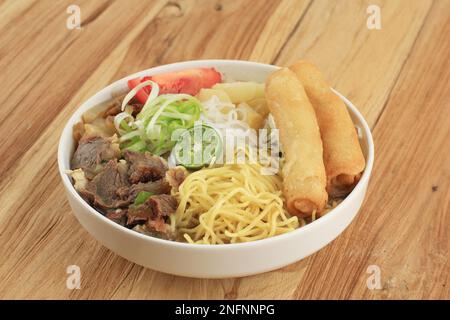 Soto Mie Bogor. Soupe traditionnelle de nouilles de bœuf Sundanese avec rouleau de printemps, chou et tomates. Street Food from Bogor, West Java, Indonésie. Isolé Banque D'Images