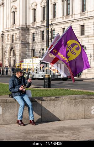 Homme blanc solitaire caucasien assis sur la place du Parlement, portant un UKIP et un drapeau anglais. Drapeau de l'indépendance du Royaume-Uni Banque D'Images