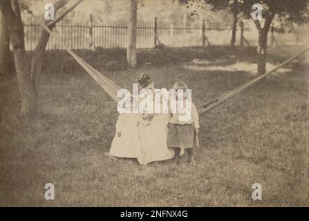 Photographie antique de c1880, mère et trois jeunes enfants dans un hamac, à l'extérieur en été. Emplacement exact inconnu, probablement Nouvelle-Angleterre, Etats-Unis. SOURCE : PHOTO ORIGINALE Banque D'Images