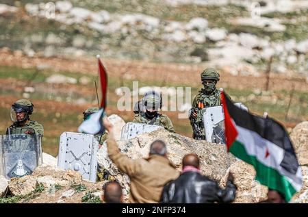 Naplouse, Palestine. 17th févr. 2023. Les manifestants palestiniens branchent des drapeaux palestiniens devant les soldats israéliens lors de la manifestation contre les colonies israéliennes dans le village de Beit Dajan, près de la ville de Naplouse, en Cisjordanie. (Photo de Nasser Ishtayeh/SOPA Images/Sipa USA) crédit: SIPA USA/Alay Live News Banque D'Images