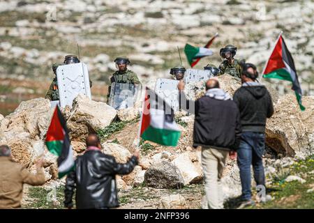 Naplouse, Palestine. 17th févr. 2023. Les manifestants palestiniens branchent des drapeaux palestiniens devant les soldats israéliens lors de la manifestation contre les colonies israéliennes dans le village de Beit Dajan, près de la ville de Naplouse, en Cisjordanie. (Photo de Nasser Ishtayeh/SOPA Images/Sipa USA) crédit: SIPA USA/Alay Live News Banque D'Images