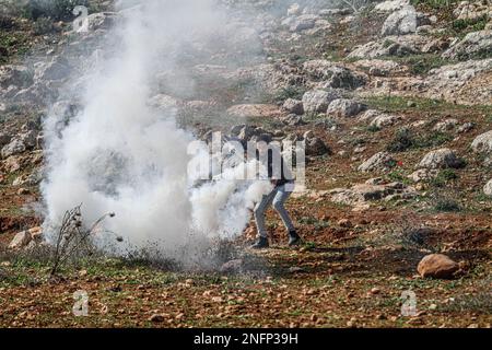 Naplouse, Palestine. 17th févr. 2023. Un manifestant palestinien jette une bombe à gaz lacrymogène après que les soldats israéliens l'ont tiré dessus lors de la manifestation contre les colonies israéliennes dans le village de Beit Dajan près de la ville de Naplouse, en Cisjordanie. (Photo de Nasser Ishtayeh/SOPA Images/Sipa USA) crédit: SIPA USA/Alay Live News Banque D'Images