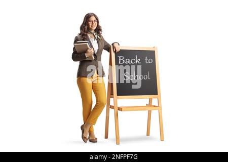 Portrait complet d'une jeune enseignante penchée sur un tableau noir avec texte de retour à l'école isolée sur fond blanc Banque D'Images