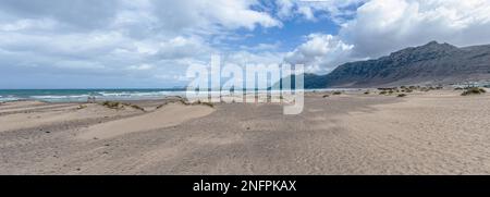Vue panoramique de la plage de Playa de Famara et de la chaîne de montagnes sur Lanzarote, les îles Canaries, contre l'océan et le ciel Banque D'Images