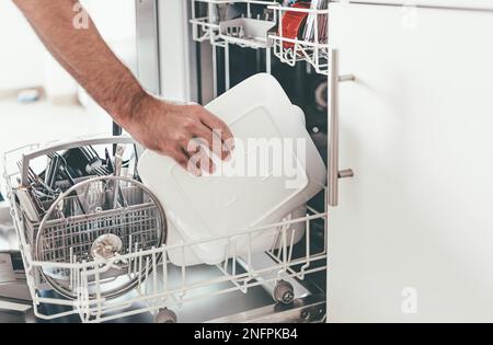 Close-up de vider personne ou le chargement d'un lave-vaisselle dans la cuisine Banque D'Images
