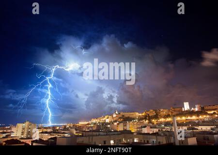 Panorama de Cagliari la nuit avec des éclairs derrière la ville. Tempête de foudre dans le ciel nocturne, au-dessus de la ville. Banque D'Images