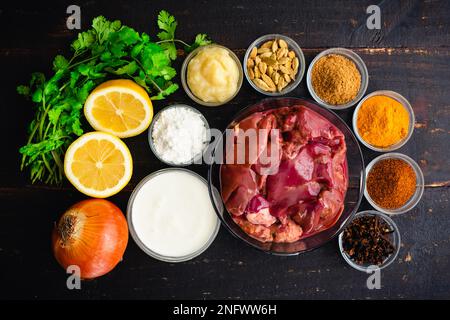 Curry de foie de poulet Ingrédients sur un bois foncé fond : foies de poulet crus, épices indiennes et autres ingrédients sur une table en bois Banque D'Images