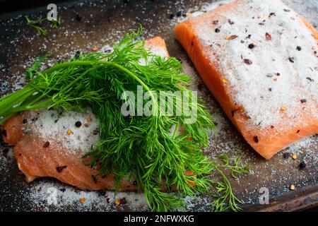 Filets de saumon couverts de sel de mer, d'épices et de dill pour faire du LOX : filets de saumon couverts de sel de mer sur une plaque pour faire du lox fait maison Banque D'Images