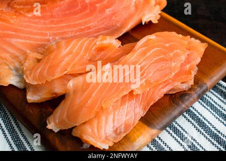 LOX fraîchement tranché sur une planche à découper en bois : vue rapprochée de tranches de saumon salé sur une planche à découper en bois Banque D'Images