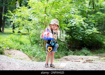 Une petite petite fille de race blanche a attrapé un insecte à la promenade dans la nature. Enfant explorant les insectes Banque D'Images