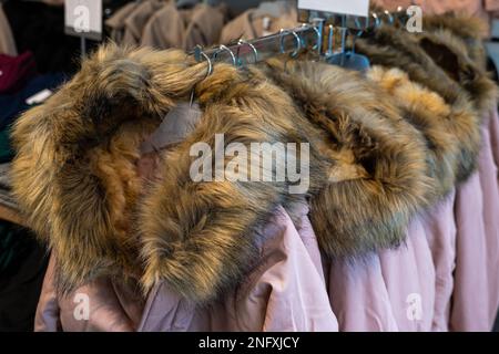 Vestes d'hiver avec colliers en fourrure accrochés à des cintres en plastique dans un magasin. Gros plan. Banque D'Images