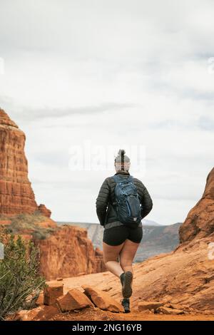 Femme randonneur se tenant sur le sentier Bell Rock dans les formations de roches rouges dans la forêt nationale de coconino à Sedona Arizona USA contre fond de nuages blancs. Banque D'Images