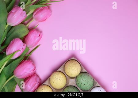 plat pondre le fond rose Pâques avec des tulipes et des oeufs colorés Banque D'Images