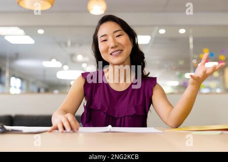 Image d'une femme asiatique ayant un appel vidéo sur un ordinateur portable au bureau Banque D'Images