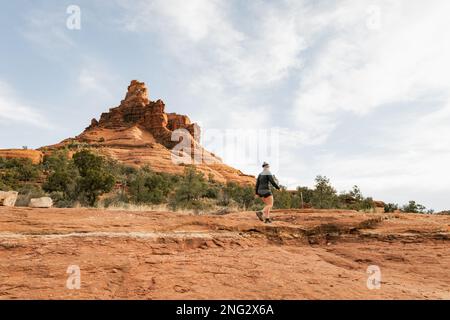 Femme randonneur se tenant sur le sentier Bell Rock dans les formations de roches rouges dans la forêt nationale de coconino à Sedona Arizona USA contre fond de nuages blancs. Banque D'Images