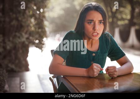 Une jeune femme qui espionne son petit ami dans un café en plein air. Tricherie Banque D'Images