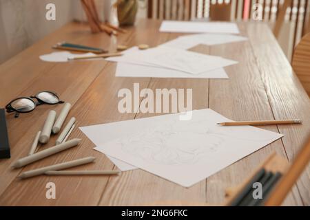 Dessin de portrait masculin, crayons et lunettes sur table en bois dans un studio d'art Banque D'Images