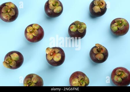 Fruits de mangoustène mûrs frais sur fond bleu clair, plat Banque D'Images