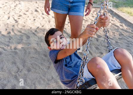 Mère et fils s'amusant à jouer avec l'oscillation dans un parc. Banque D'Images