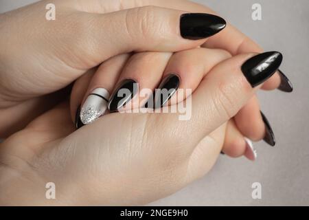 ongles prolongés avec manucure noire et blanche sur fond gris, manucure féminine Banque D'Images