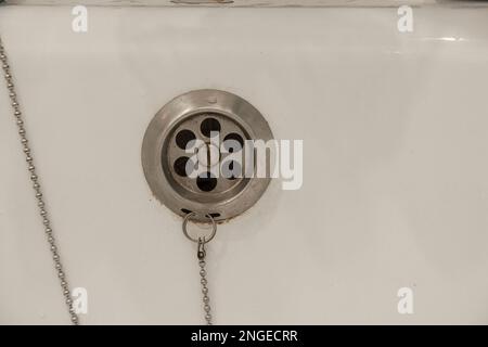 Eau de drainage avec bouchon en caoutchouc de drainage sur la baignoire de douche blanche de près Banque D'Images