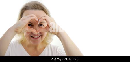 Portrait de bannière de la belle femme asiatique sur le sourire blanc de chemise et le geste de main en forme de coeur montrant l'amour, le soutien au personnel médical, la charité, la campagne de don. Journée mondiale du coeur, la santé de la femme Banque D'Images