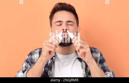 Homme utilisant des sprays nasaux sur fond pêche Banque D'Images