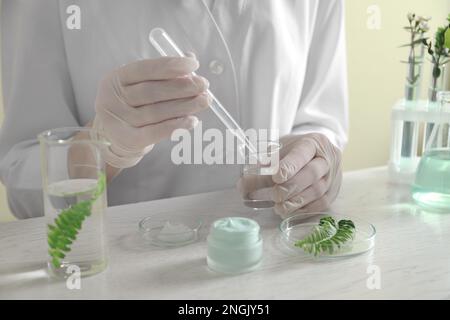 Scientifique faisant des produits cosmétiques à la table blanche en laboratoire, gros plan Banque D'Images