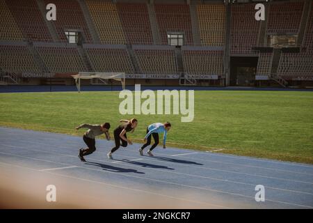 Deux femmes et un homme ont juste commencé à sprint au stade Banque D'Images