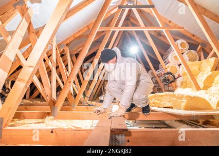 l'homme isole le toit et le plafond de la maison avec de la laine de verre Banque D'Images