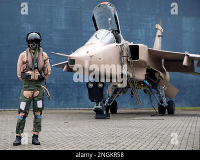 Pilote de chasse, RAF, debout avec Fighter Jet prêt pour une mission de combat portant casque volant, costume et visière sombre avec masque à oxygène Royal Air Force. Banque D'Images