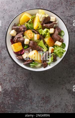 Salade chaude française aux gésiers ou salade chaude aux gesiers, dans une assiette sur la table. Vue verticale du dessus Banque D'Images