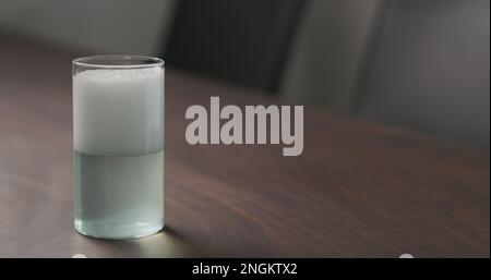 versez la boisson gazeuse verte d'une bouteille dans le verre à bille haute sur la table en noyer avec espace de copie, photo large Banque D'Images